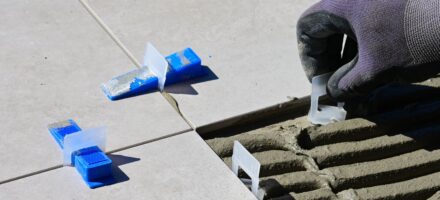 Vloertegel wordt op tegellijm gelegd met levelers en spacers