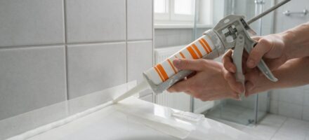 Met een kitpistool wordt sanitairkit langs de badrand aangebracht tussen afplaktape